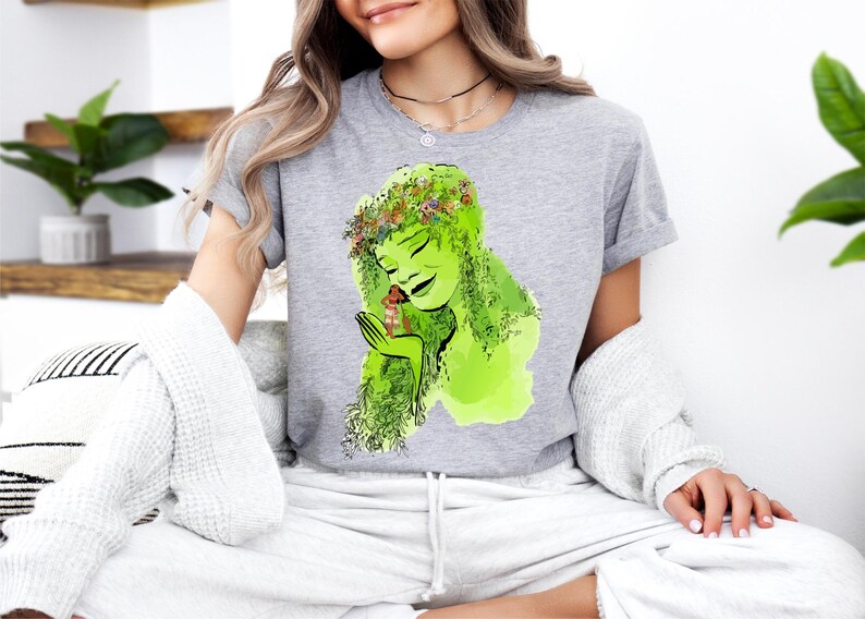 a woman sitting on a couch wearing a t - shirt with a picture of a