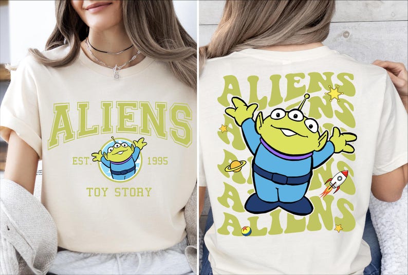 Puede incluir: Una camiseta blanca con un personaje extraterrestre verde de Toy Story. La parte delantera de la camiseta dice "Aliens Est. 1995 Toy Story". La parte trasera de la camiseta tiene un patr&oacute;n repetido del personaje extraterrestre y la palabra "Aliens" en una fuente retro.