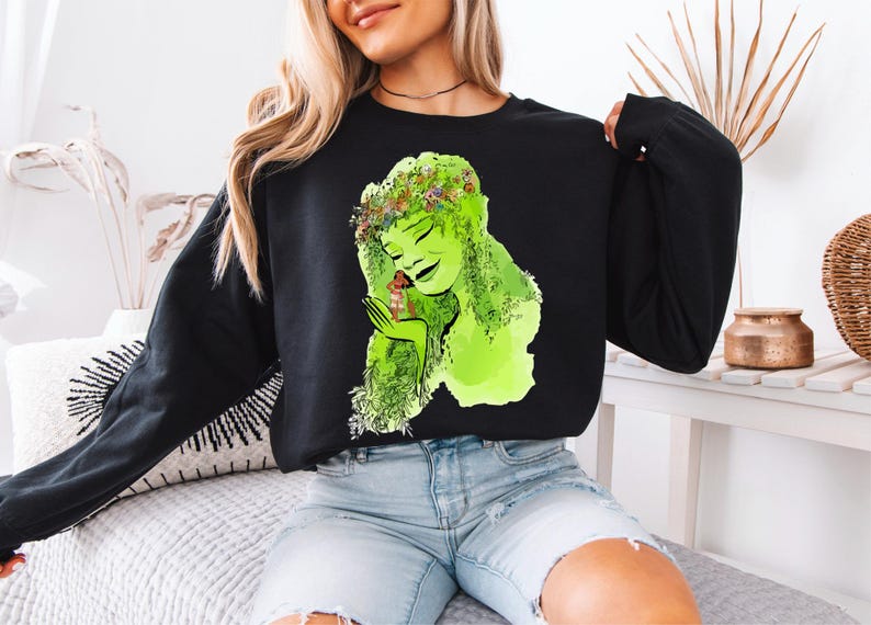 a woman sitting on a bed wearing a black shirt with a picture of a woman