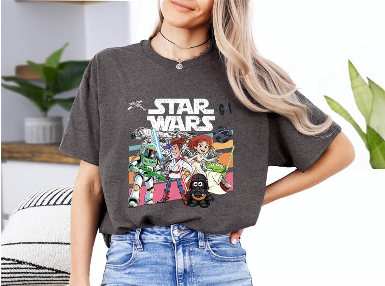A woman wearing a gray t-shirt with a Star Wars graphic and cartoon characters, including a character holding a sword and a character with a green hat.