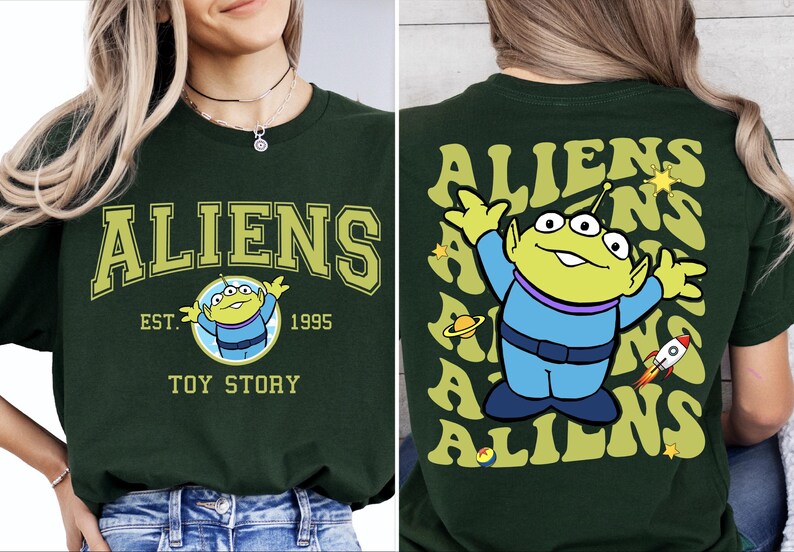 Puede incluir: Camiseta verde con un gr&aacute;fico de un extraterrestre de tres ojos de Toy Story. La parte delantera de la camiseta dice "Aliens Est. 1995 Toy Story". La parte trasera de la camiseta tiene un patr&oacute;n repetido del extraterrestre y la palabra "Aliens" en una fuente retro.