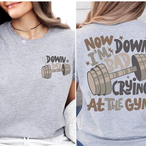 a woman wearing a gray shirt with a barbell on it
