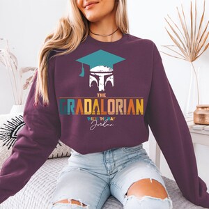 a woman sitting on a bed wearing a purple sweatshirt