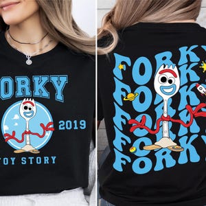 May include: Black t-shirt featuring a blue and red cartoon character of Forky from Toy Story. The front of the shirt reads "Forky Est. 2019 Toy Story". The back of the shirt has a repeating pattern of the word "Forky" in blue.