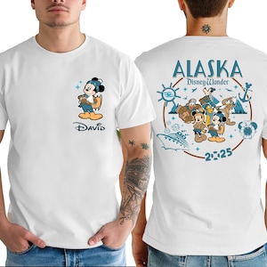 A white t-shirt with a graphic design featuring a cartoon character and various Disney-themed elements, along with the text "Alaska Disney Wonder" and the year "2025".