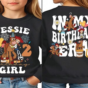 a young girl wearing a black sweatshirt with cartoon characters on it
