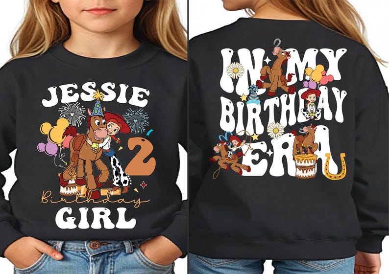 a young girl wearing a black sweatshirt with cartoon characters on it