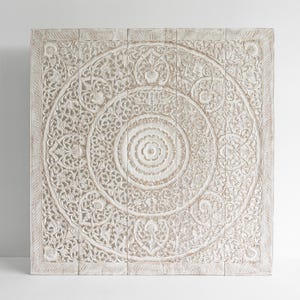 May include: White wooden wall decor with intricate carved floral patterns in a circular design.