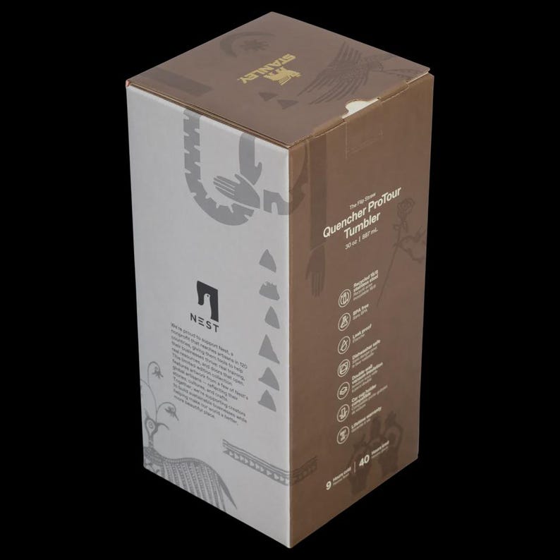 Puede incluir: Una caja de vaso Stanley Quencher ProTour. La caja es blanca y marr&oacute;n con el logotipo de Stanley y la informaci&oacute;n del producto. La caja tiene un dise&ntilde;o gr&aacute;fico con la palabra "NEST" impresa en el lateral.