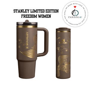 Puede incluir: Dos vasos Stanley Limited Edition Freedom Women marrones. Uno es una taza con asa, el otro es un vaso de viaje. Ambos tienen dise&ntilde;os florales y de p&aacute;jaros dorados. El logotipo de Stanley es visible en ambos. El texto "STANLEY LIMITED EDITION FREEDOM WOMEN" est&aacute; en la parte superior.