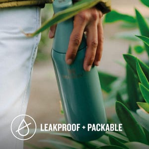 Może przedstawiać: Zielona, wielorazowa butelka na wodę z wodoodpornym designem. Butelka jest trzymana przez rękę. Na butelce widnieje napis "LEAKPROOF + PACKABLE".