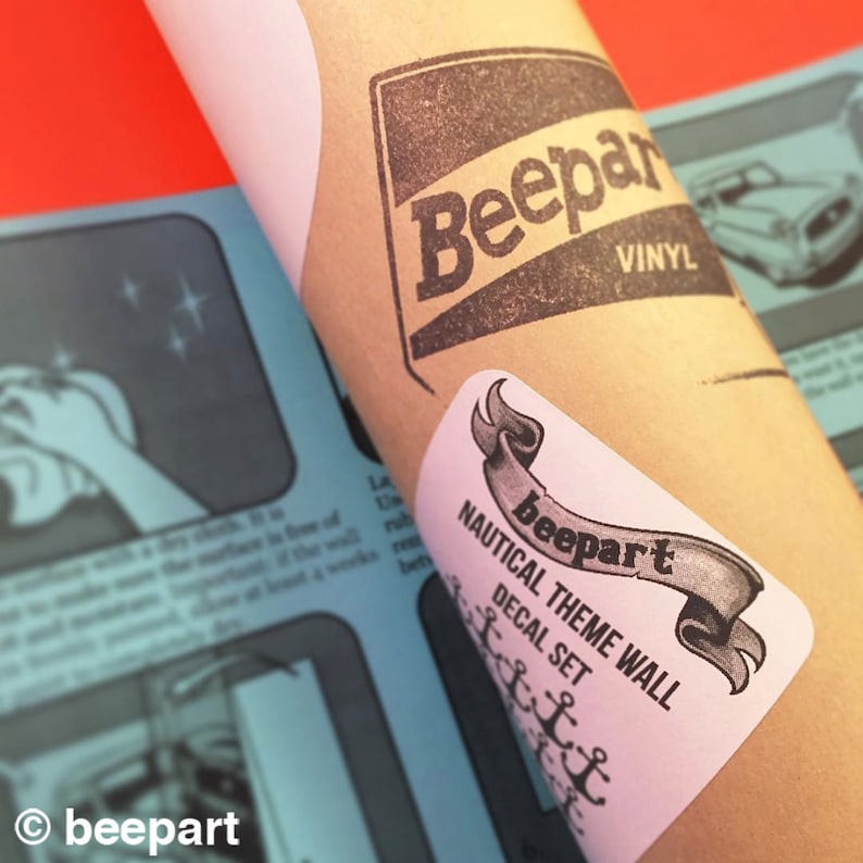 May include: A brown paper tube with a white sticker that says "Nautical Theme Wall Decal Set" and a black and white illustration of a ribbon with the word "beepart" on it. The tube also has a black and white sticker that says "Beepart Vinyl".
