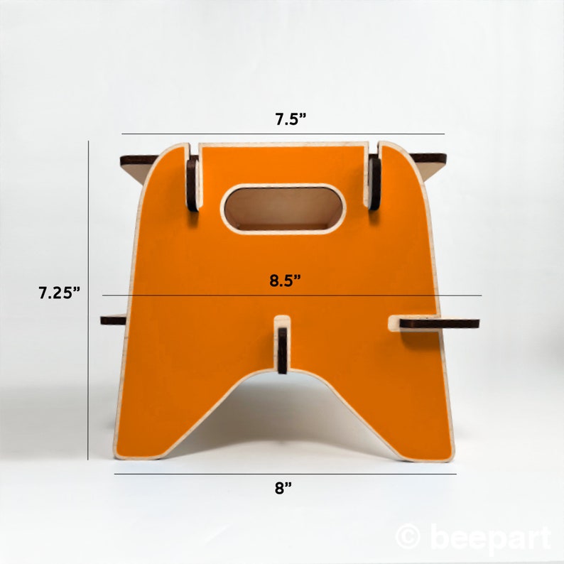 May include: Orange wooden step stool with a cutout handle. The stool measures 7.5 inches wide, 8 inches deep, and 7.25 inches tall.