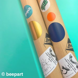 May include: Two brown cardboard tubes with colorful vinyl stickers. The stickers feature retro space-themed designs, including stars, rockets, and the text "beepart".