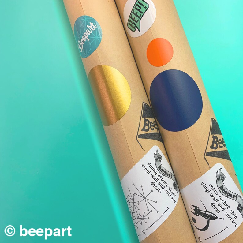 May include: Two brown cardboard tubes with colorful vinyl stickers. The stickers feature retro space-themed designs, including stars, rockets, and the text "beepart".
