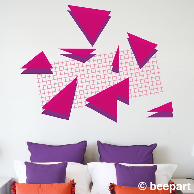 May include: Pink and purple geometric triangle wall decals with a grid pattern on a white wall. The decals are arranged in a random pattern and are a modern and stylish way to decorate a room.