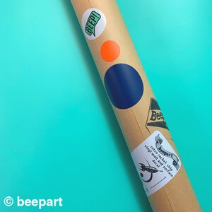 May include: A brown cardboard tube with a blue and orange circle sticker, a green sticker with the word "BEEP!" and a white sticker with the text "beepart retro rocket ship vinyl wall and surface decal".