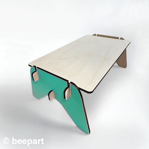 May include: A light wood table with a teal green base. The table is made of plywood and has a simple, modern design.