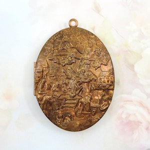 May include: An antique oval-shaped locket with a detailed relief scene. The locket is made of a bronze-colored metal and features a hinged design. The relief depicts figures, a tree, and architectural elements, creating a historical aesthetic.