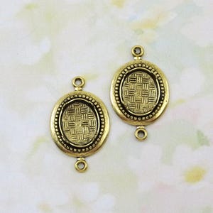 May include: Two antique gold-colored oval jewelry connectors. Each connector features a woven pattern within an oval frame, surrounded by a beaded border. They have loops at the top and bottom for attaching to other jewelry components.
