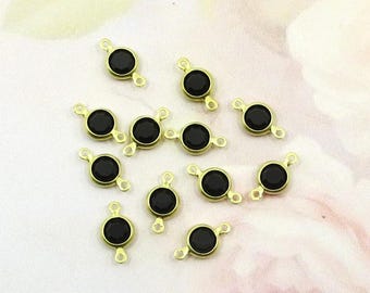 May include: Gold-toned metal connectors with a black, round gemstone center. Each connector has two small loops for attaching to other jewelry components. The gemstones are evenly spaced on a soft, pink and white background.