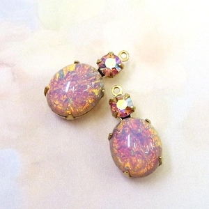 May include: Two vintage-style earrings. Each earring features an oval, iridescent pink and gold stone set in a gold-tone metal frame. A smaller, iridescent crystal is set above the oval stone. The earrings have a loop for hanging.