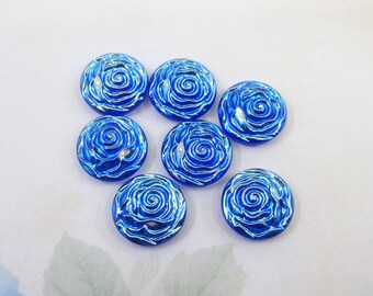 May include: Seven blue glass cabochons with a white iridescent rose design. The cabochons are round and have a smooth, glossy finish.
