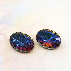 May include: Two oval-shaped, iridescent crystals with a faceted design. The crystals display a spectrum of colors, including blue, purple, and orange, with a golden edge. These could be used for jewelry making or other crafts.