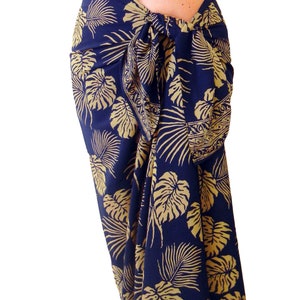 Midnight blue sarong with large jungle leaves in tan. It is tied in a knot at the hips and covers to the feet, worn as a full-length skirt.