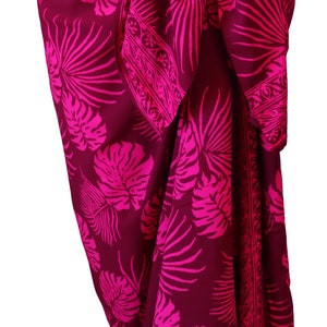 Maroon sarong with large hot pink jungle leaves. It is tied in a knot at the hips and covers to the feet, worn as a full-length skirt or beach cover up.