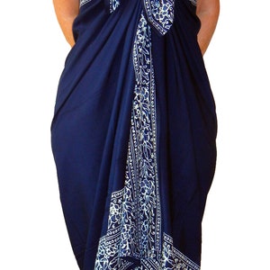 Navy blue sarong with a  white floral border that goes all the way around on all four sides. It is tied as a dress with a bow at the breast line. The border design flows down the front, across the breast line, and hems the bottom at the knee.