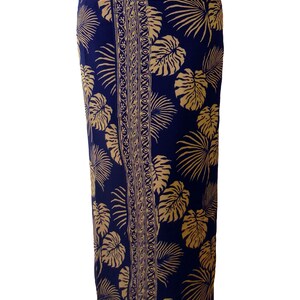Midnight blue sarong with large jungle leaves in tan. It is worn as a straight skirt and falls to the feet. The border design goes from waist to feet, shown as slightly to one side.