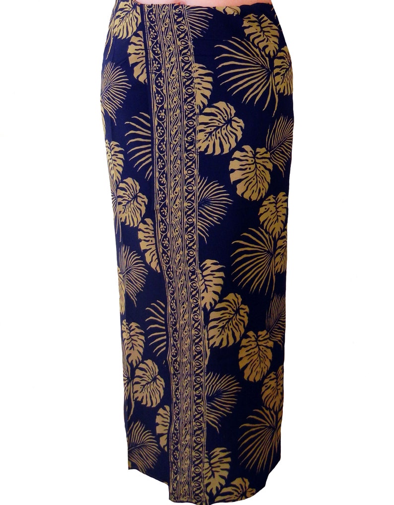 Midnight blue sarong with large jungle leaves in tan. It is worn as a straight skirt and falls to the feet. The border design goes from waist to feet, shown as slightly to one side.