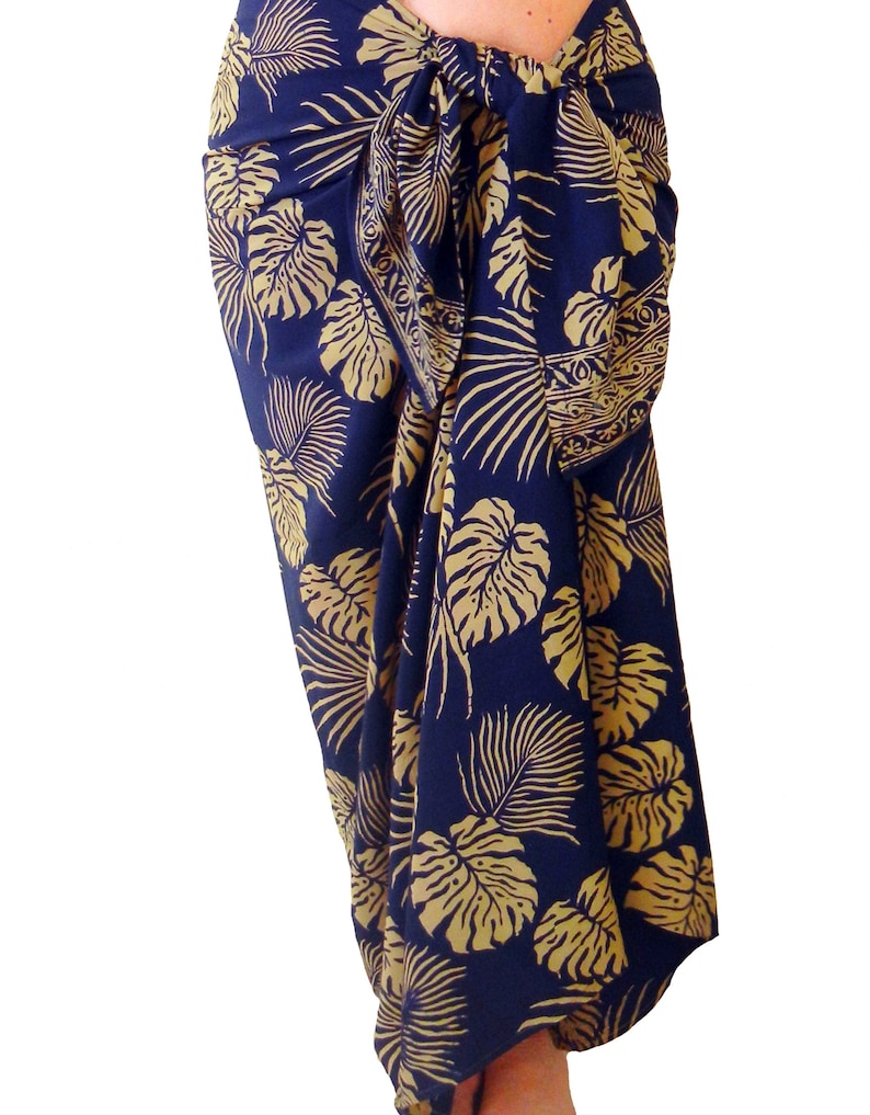 Midnight blue sarong with large jungle leaves in tan. It is tied in a knot at the hips and covers to the feet, worn as a full-length skirt.