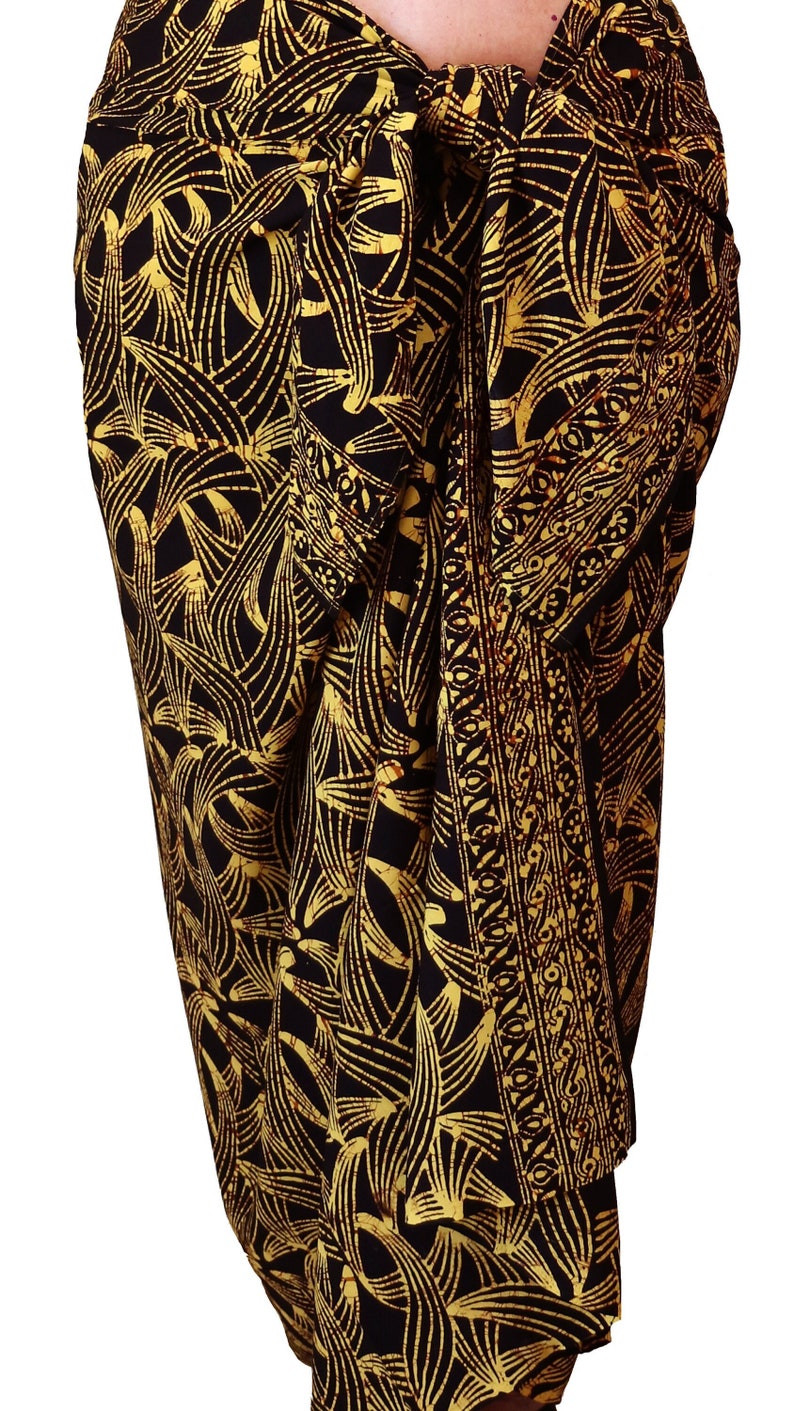 Black. brown and golden yellow sarong with a bit of brown crackly batik texture throughout. It is wrapped around the waist and tied in a knot. There is a lovely border design that drapes down the front.