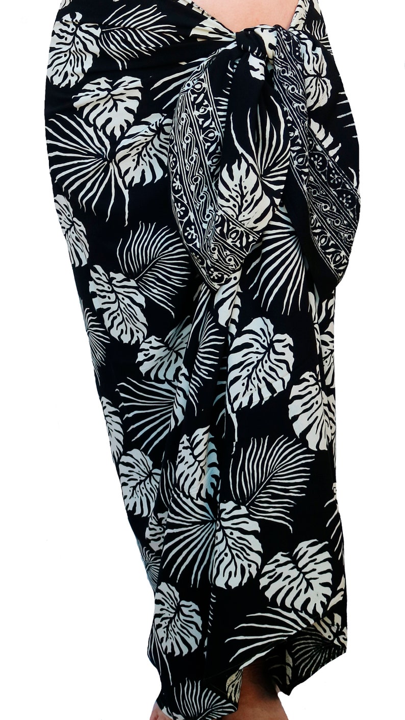 Black & Creamy White sarong with a large, creamy white, jungle leaves motif. It is tied in a knot at the hips and covers to the feet, worn as a full-length skirt.