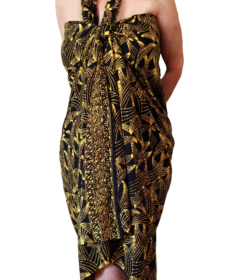 Black sarong dress with a pattern in golden yellow with brown batik crackling. The pattern is like floating leaves intermingling. It is tied around the neck and lays beautifully from chest to knees with the border pattern falling down the front.