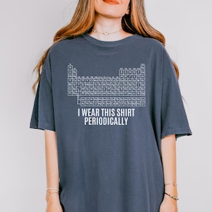 Puede incluir: Camiseta azul oscuro con una tabla periódica blanca y el texto "I WEAR THIS SHIRT PERIODICALLY". Una camiseta cómoda para los amantes de la ciencia. Corte holgado.