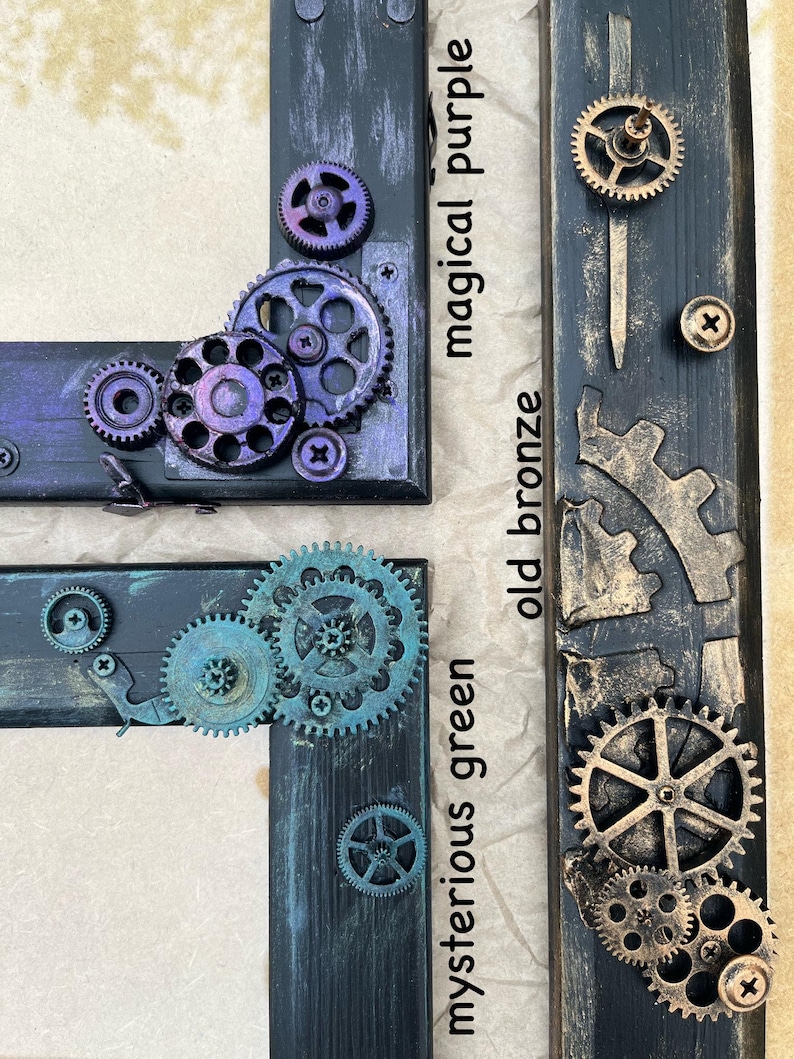 May include: Three wooden picture frames with different colored paint finishes. The frames are decorated with metal gears and have the words "mysterious green", "old bronze", and "magical purple" written on them.