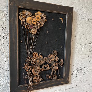 May include: A framed artwork featuring a heart-shaped balloon made of buttons and gears, with a pair of Mickey Mouse characters made of gears and metal pieces below. The background is black with white stars and a crescent moon.