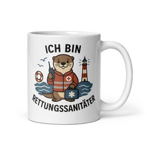 May include: White ceramic mug featuring a cartoon otter in a red jacket with a cross emblem, holding a radio and a medical bag. The mug has the text "ICH BIN RETTUNGSSANITÄTER" and images of a lighthouse, waves, and a life preserver.