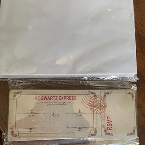 May include: A stack of white blank cards and a stack of Hogwarts Express invitation cards. The invitation cards are tan with red and brown accents, featuring text fields for date, place, and time, and a RSVP stamp.
