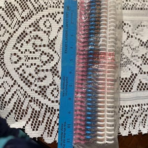 May include: A package of hair rollers in pink, blue, and white, with a blue ruler next to it. The ruler is marked with inches and has text that says "Cass County Sheriff's Office" and "Kids Who Rule Out Drugs Always Measure Up!"