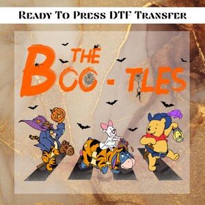 May include: A DTF transfer featuring a Halloween-themed design with the text "The Boo-tles" in orange. The image includes cartoon characters dressed in Halloween costumes, with bats and spiders scattered around.