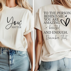 May include: A white t-shirt with the text "You Matter" on the front and "To the person behind me: You are amazing + beautiful and enough. Remember that" on the back.
