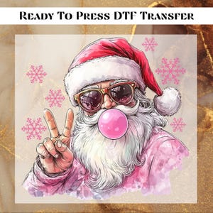 May include: A pink and white Santa Claus wearing sunglasses and blowing a pink bubble. He is giving the peace sign with his left hand. The background is a light brown with pink snowflakes.