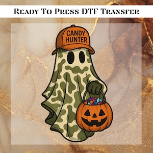 May include: A Halloween-themed DTF transfer design featuring a cartoon ghost wearing an orange cap with "CANDY HUNTER" text. The ghost is draped in a camouflage-patterned sheet and carries a jack-o'-lantern filled with candy. The text "READY TO PRESS DTF TRANSFER" is at the top.