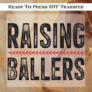 May include: Ready to Press DTF Transfer design with black text that reads "Raising Ballers" with a red baseball stitch design between the words.