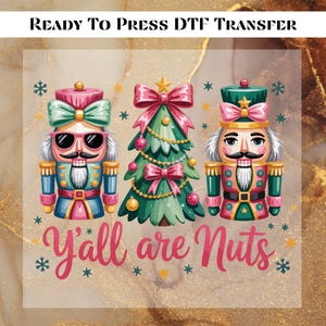 May include: A DTF transfer featuring two nutcracker figures and a Christmas tree. The nutcrackers are in blue, pink, and green uniforms, with sunglasses and a mustache. The Christmas tree is decorated with pink bows and ornaments. The text "Y'all are Nuts" is also included.