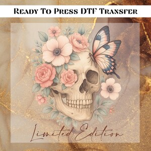 May include: DTF transfer design featuring a skull adorned with pink roses, flowers, and a butterfly. The words "READY TO PRESS DTF TRANSFER" and "Limited Edition" are printed at the top and bottom of the design, respectively. The background has a gold and brown marble effect.
